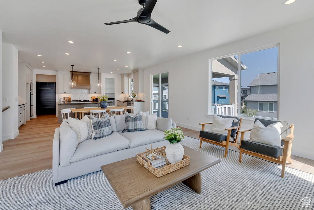 Living room with ceiling fan and light hardwood / wood-style floors