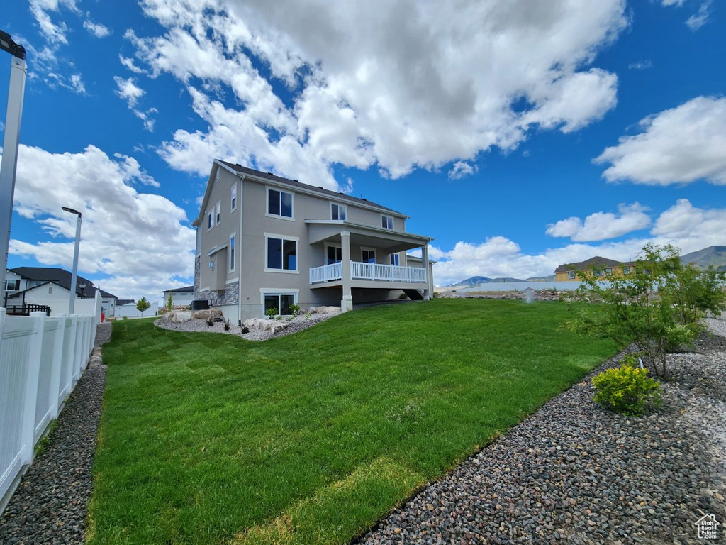 Back of property featuring a lawn and a balcony