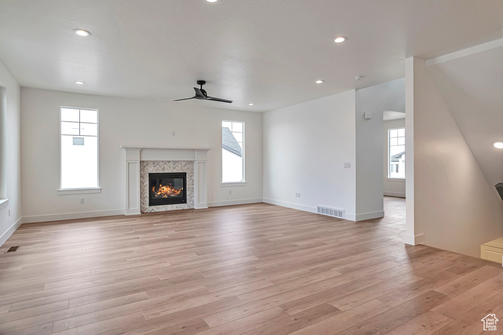 Unfurnished living room featuring light wood-type flooring, ceiling fan, and a fireplace