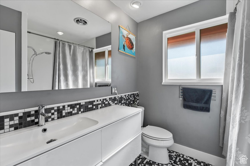 Bathroom featuring plenty of natural light, toilet, tile flooring, and vanity