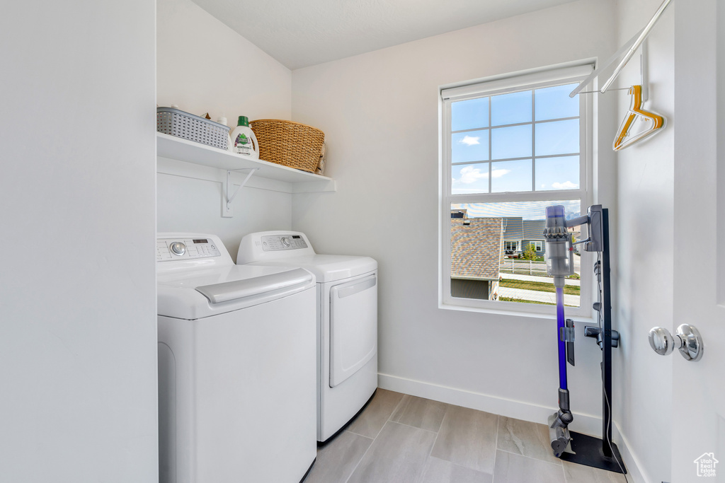 Washroom featuring plenty of natural light, independent washer and dryer, and light tile flooring