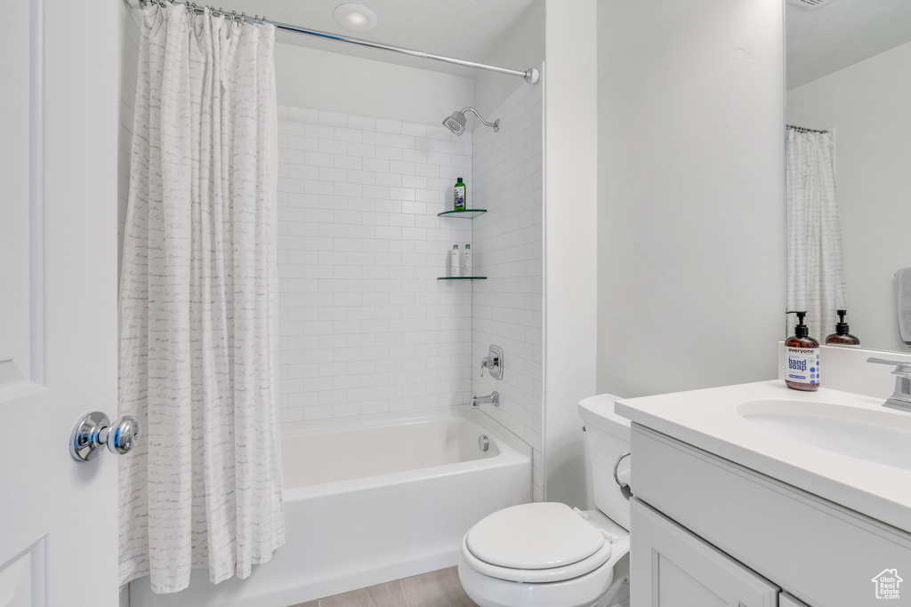 Full bathroom featuring hardwood / wood-style flooring, oversized vanity, shower / bath combo, and toilet