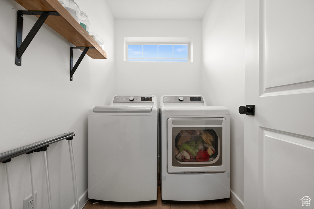 Washroom with hardwood / wood-style flooring and washing machine and clothes dryer
