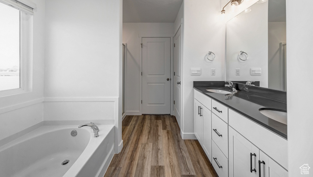 Bathroom featuring double vanity, a bathtub, and hardwood / wood-style floors