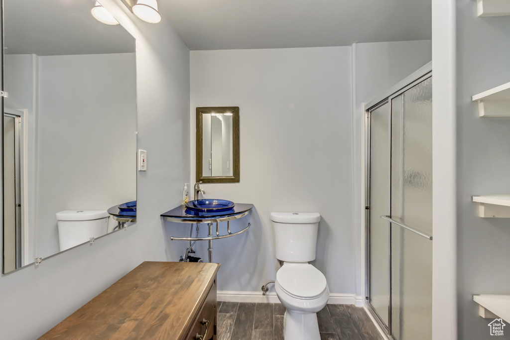 Bathroom featuring wood-type flooring, vanity, toilet, and a shower with shower door