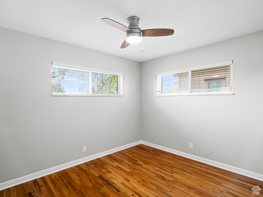 Spare room with a wealth of natural light, dark hardwood / wood-style flooring, and ceiling fan