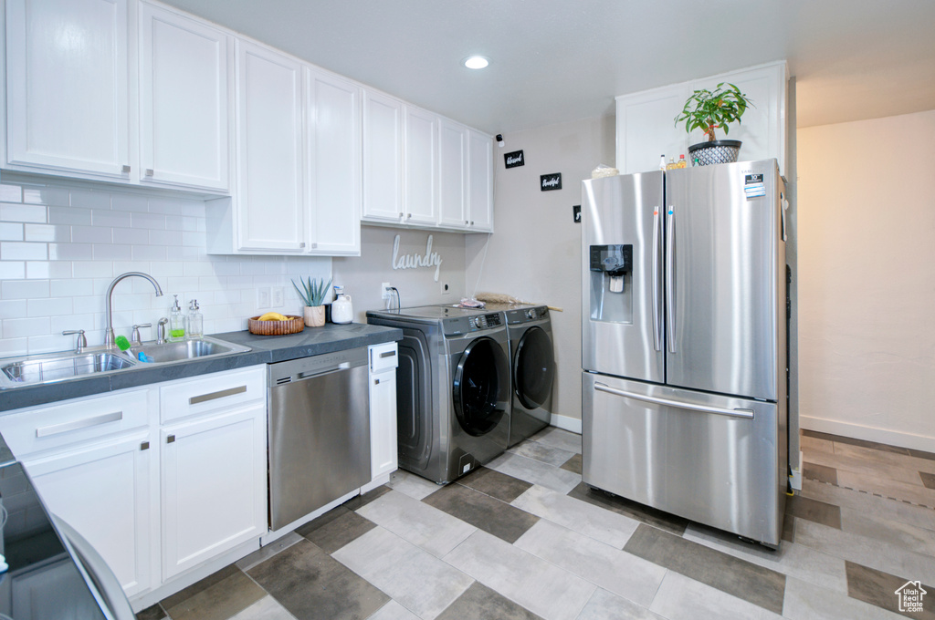 Kitchen with white cabinetry, separate washer and dryer, backsplash, stainless steel appliances, and sink
