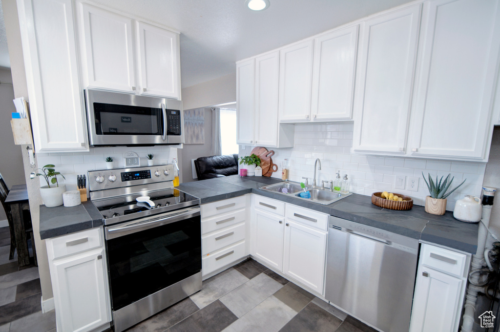 Kitchen featuring tasteful backsplash, appliances with stainless steel finishes, white cabinetry, and sink
