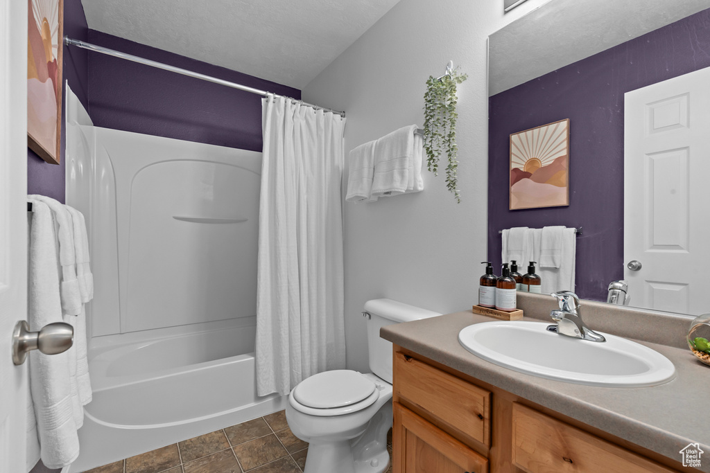 Full bathroom with shower / tub combo, vanity with extensive cabinet space, toilet, and tile flooring