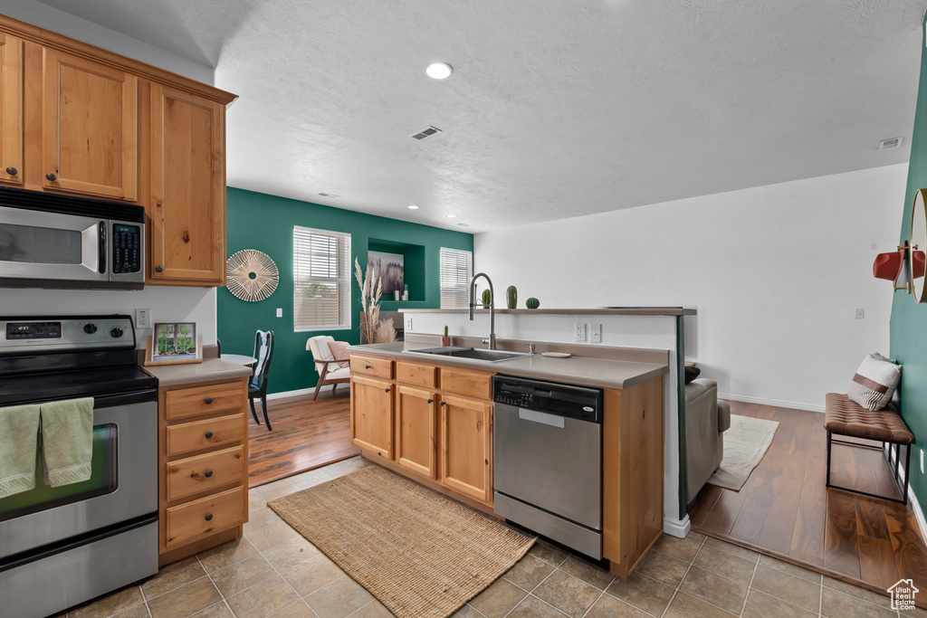 Kitchen with sink, appliances with stainless steel finishes, and light tile flooring