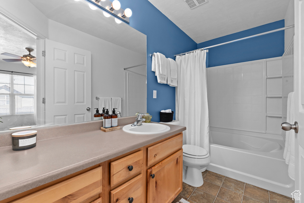 Full bathroom featuring tile flooring, ceiling fan, toilet, vanity, and shower / bathtub combination with curtain