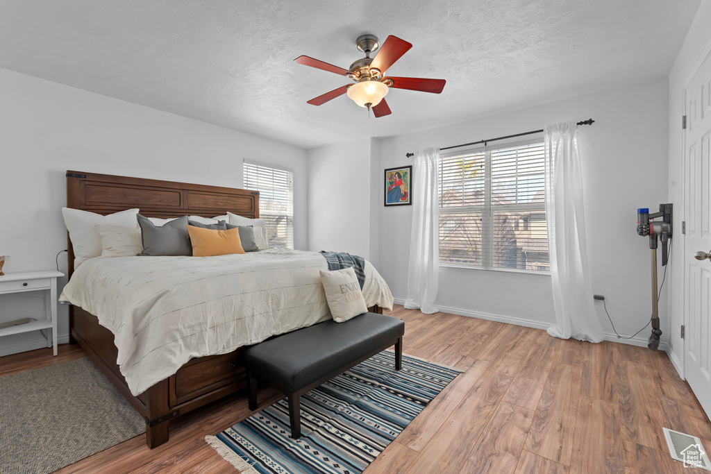Bedroom featuring wood-type flooring, ceiling fan, and multiple windows