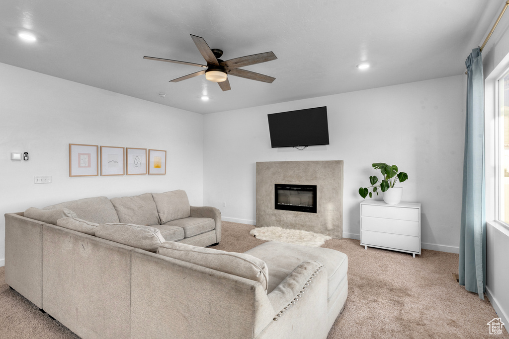 Carpeted living room featuring a healthy amount of sunlight, ceiling fan, and a fireplace