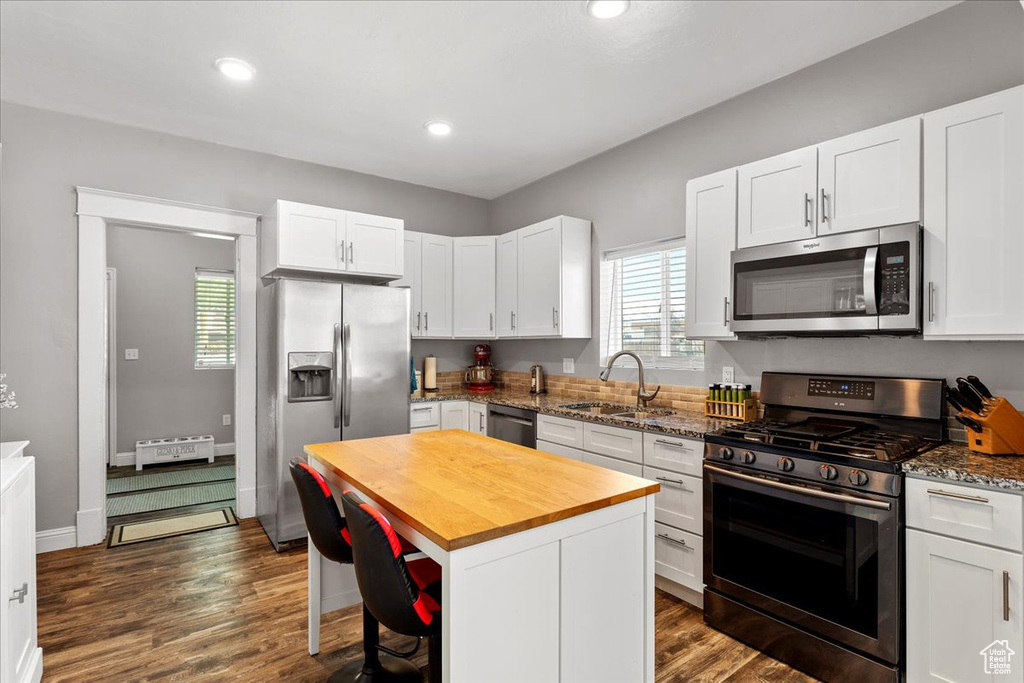 Kitchen featuring a center island, appliances with stainless steel finishes, dark hardwood / wood-style flooring, and sink