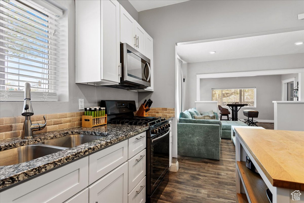 Kitchen featuring dark wood-type flooring, white cabinetry, sink, tasteful backsplash, and black gas range