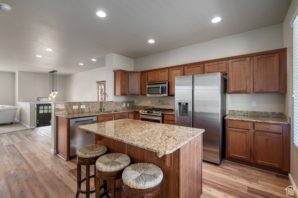 Kitchen featuring a center island, decorative light fixtures, light hardwood / wood-style flooring, stainless steel appliances, and sink