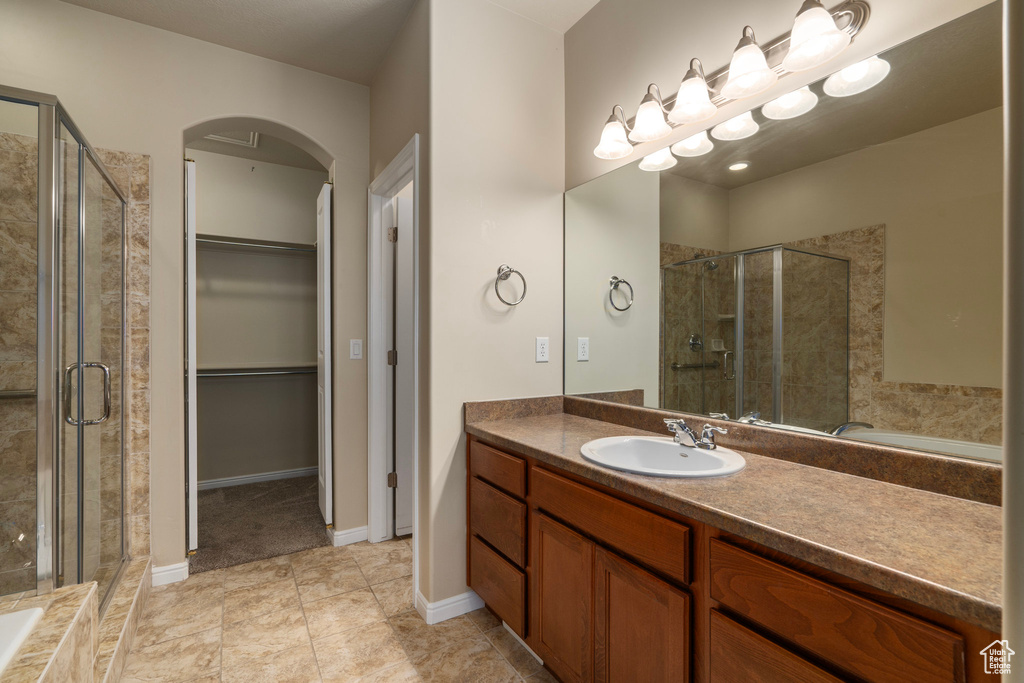 Bathroom with vanity with extensive cabinet space, tile flooring, and independent shower and bath