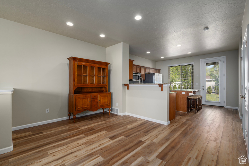 Interior space with refrigerator, kitchen peninsula, hardwood / wood-style flooring, and a kitchen bar