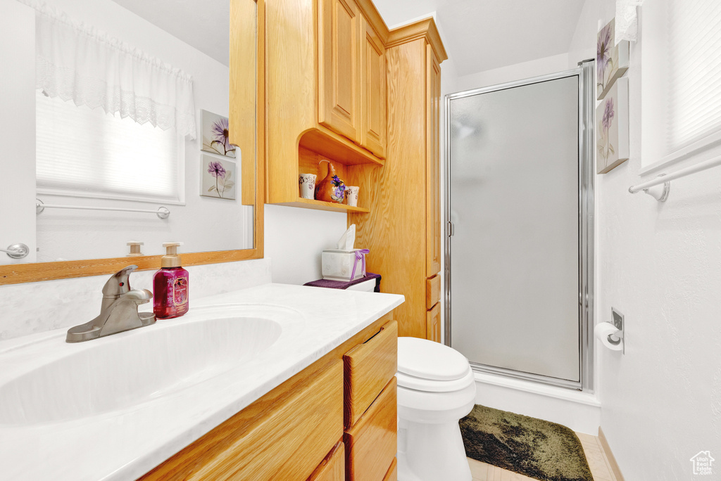 Bathroom featuring a wealth of natural light, toilet, vanity, and walk in shower