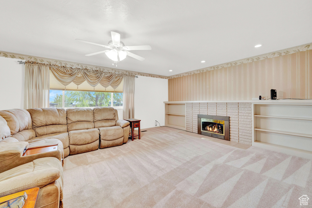 Living room with a brick fireplace, ceiling fan, and carpet floors