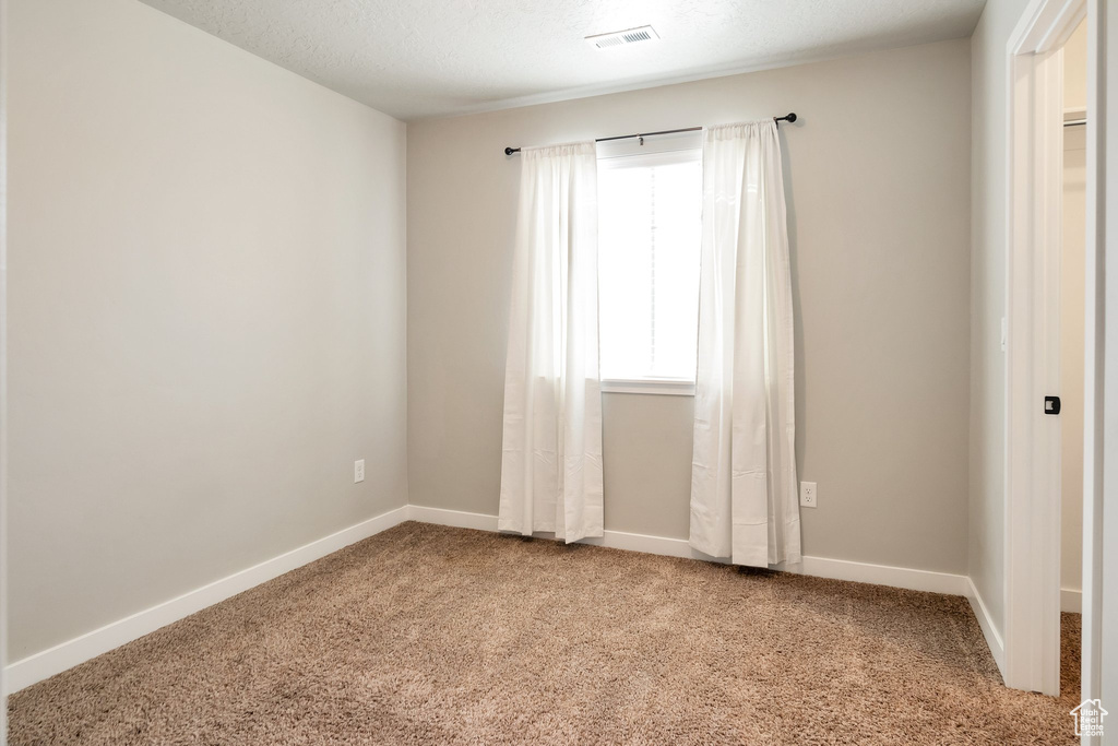 Spare room with carpet flooring and a textured ceiling