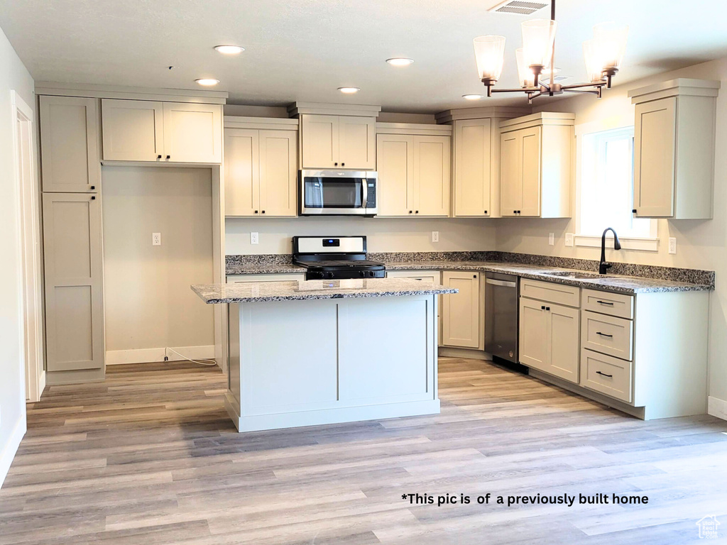 Kitchen featuring light hardwood / wood-style flooring, stainless steel appliances, sink, pendant lighting, and a center island