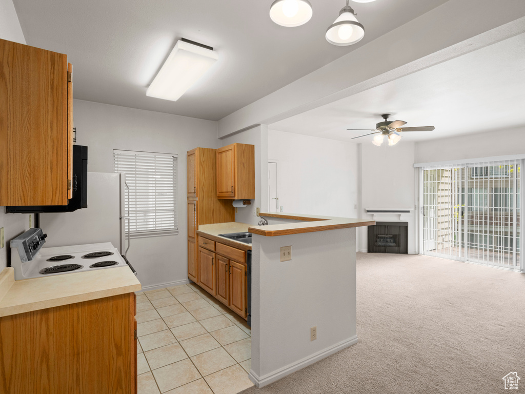 Kitchen with ceiling fan, light carpet, sink, white electric range oven, and kitchen peninsula