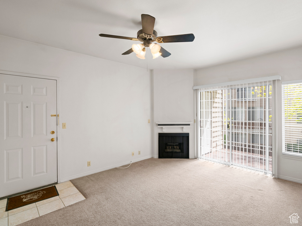 Unfurnished living room featuring ceiling fan and carpet floors
