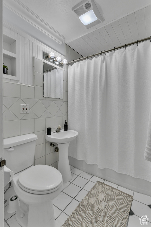 Bathroom featuring built in features, toilet, tile floors, and tile walls
