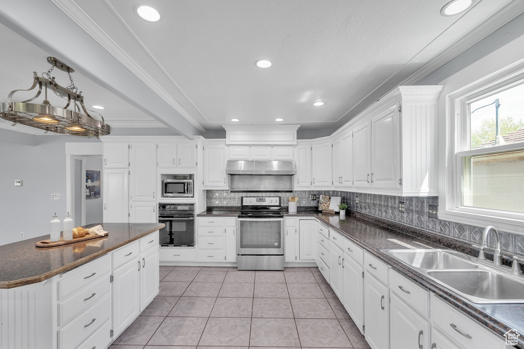 Kitchen featuring appliances with stainless steel finishes, backsplash, white cabinetry, sink, and light tile floors