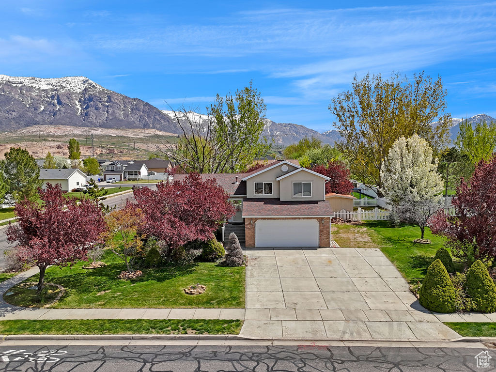 View of front of property featuring a garage, a mountain view, and a front yard