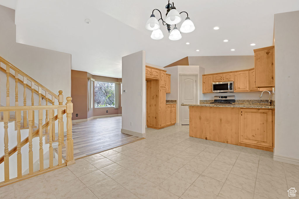 Kitchen featuring light wood-type flooring, light stone countertops, lofted ceiling, sink, and an inviting chandelier