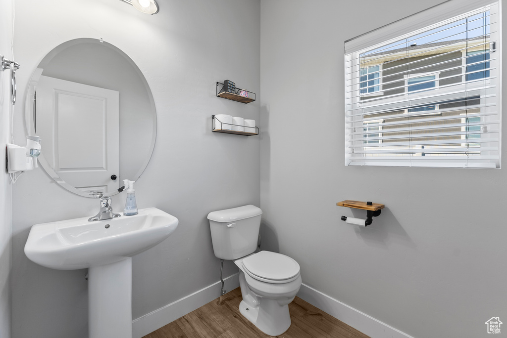 Bathroom featuring hardwood / wood-style flooring, a healthy amount of sunlight, and toilet