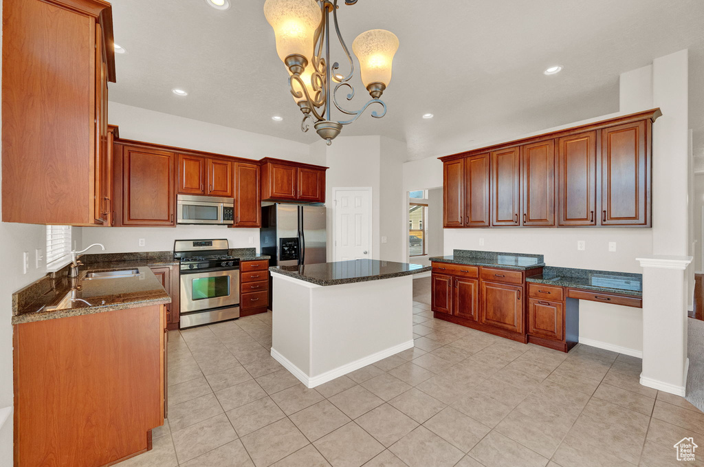 Kitchen with decorative light fixtures, stainless steel appliances, light tile floors, sink, and a kitchen island