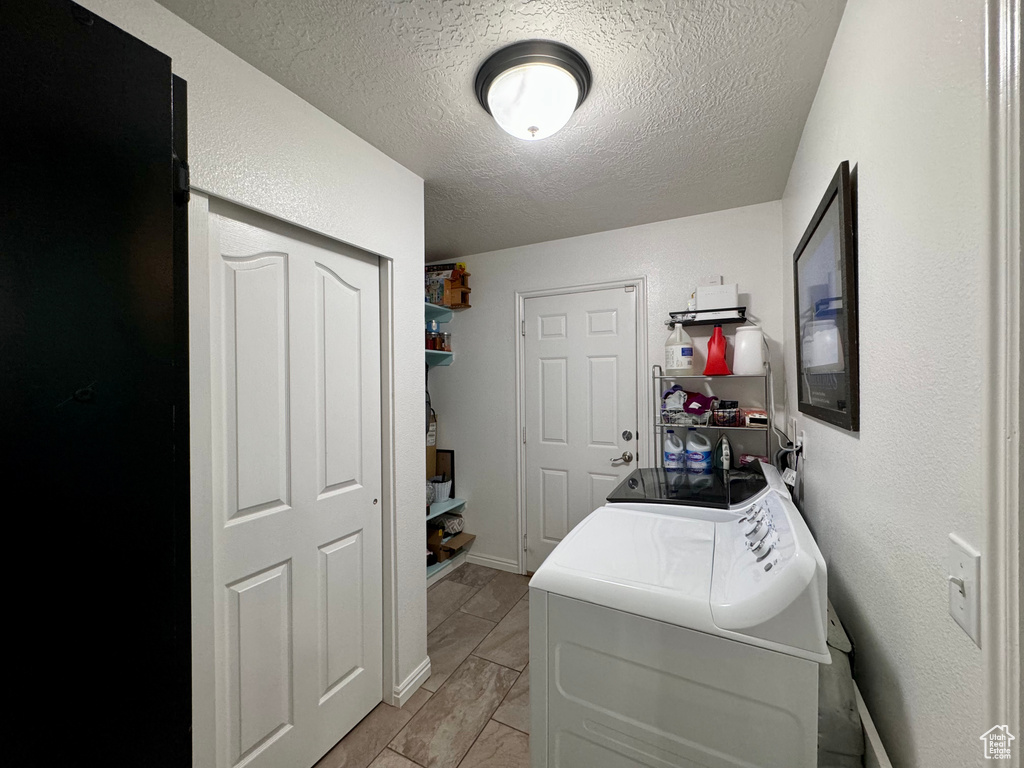 Laundry room featuring independent washer and dryer, a textured ceiling, and light tile flooring