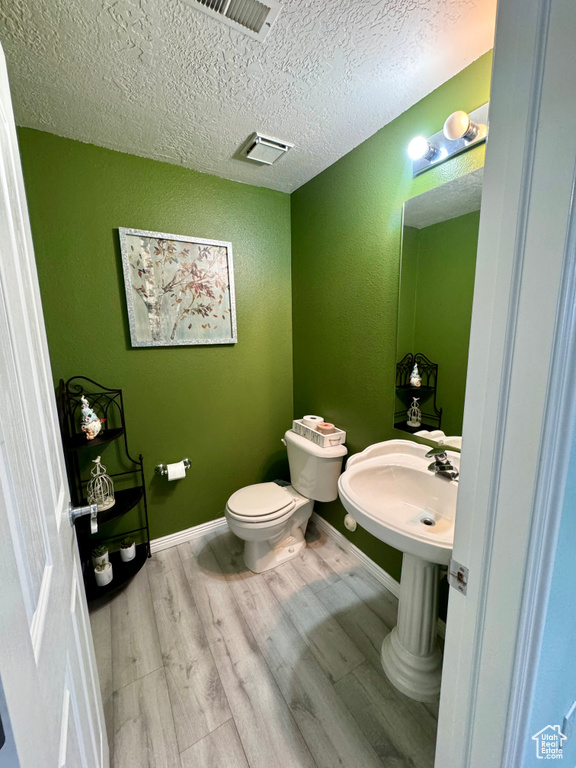 Bathroom featuring a textured ceiling, hardwood / wood-style flooring, and toilet