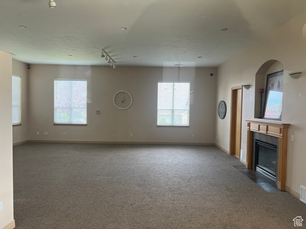 Unfurnished living room featuring rail lighting and carpet floors