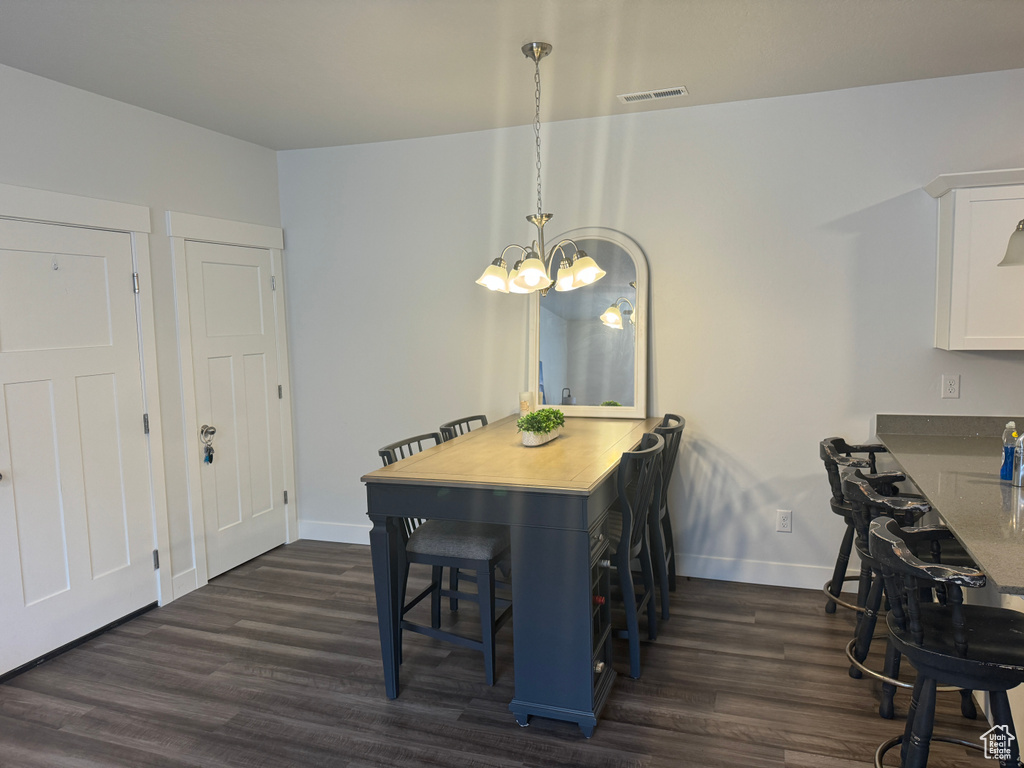 Dining space with dark hardwood / wood-style floors and a notable chandelier