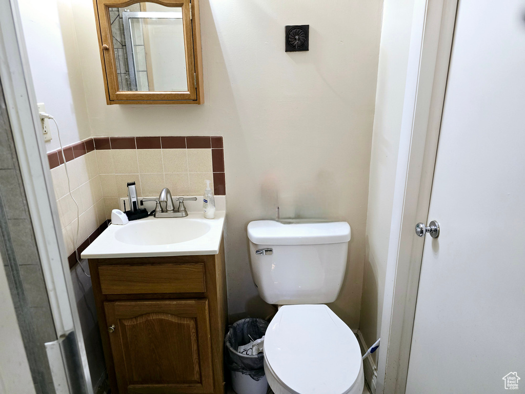 Bathroom featuring vanity, tasteful backsplash, and toilet