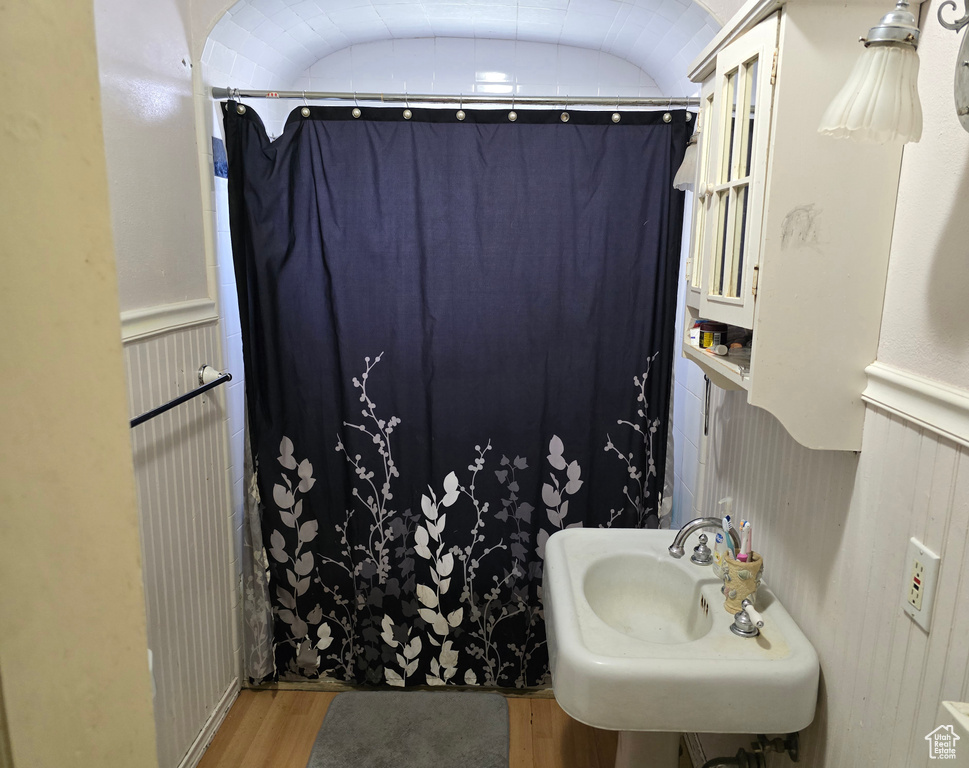 Bathroom with sink, hardwood / wood-style floors, and vaulted ceiling