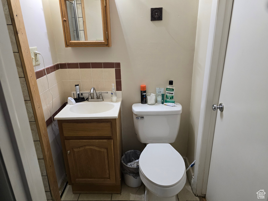 Bathroom with tasteful backsplash, toilet, tile floors, and vanity