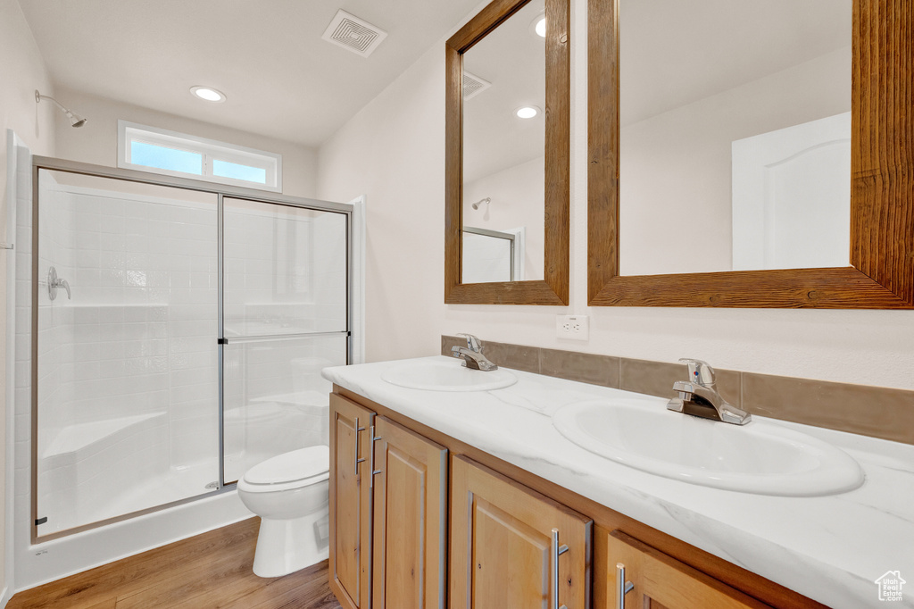 Bathroom with double sink vanity, hardwood / wood-style flooring, toilet, and walk in shower