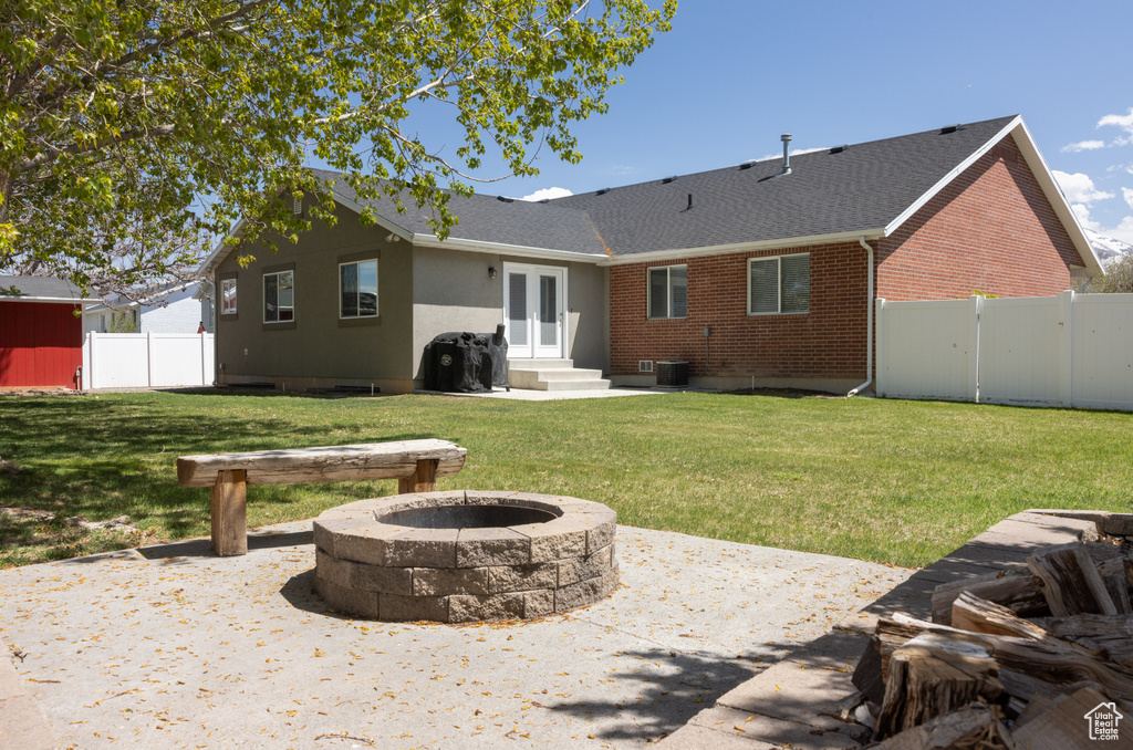 Back of house with a patio area, an outdoor fire pit, a lawn, and central AC unit