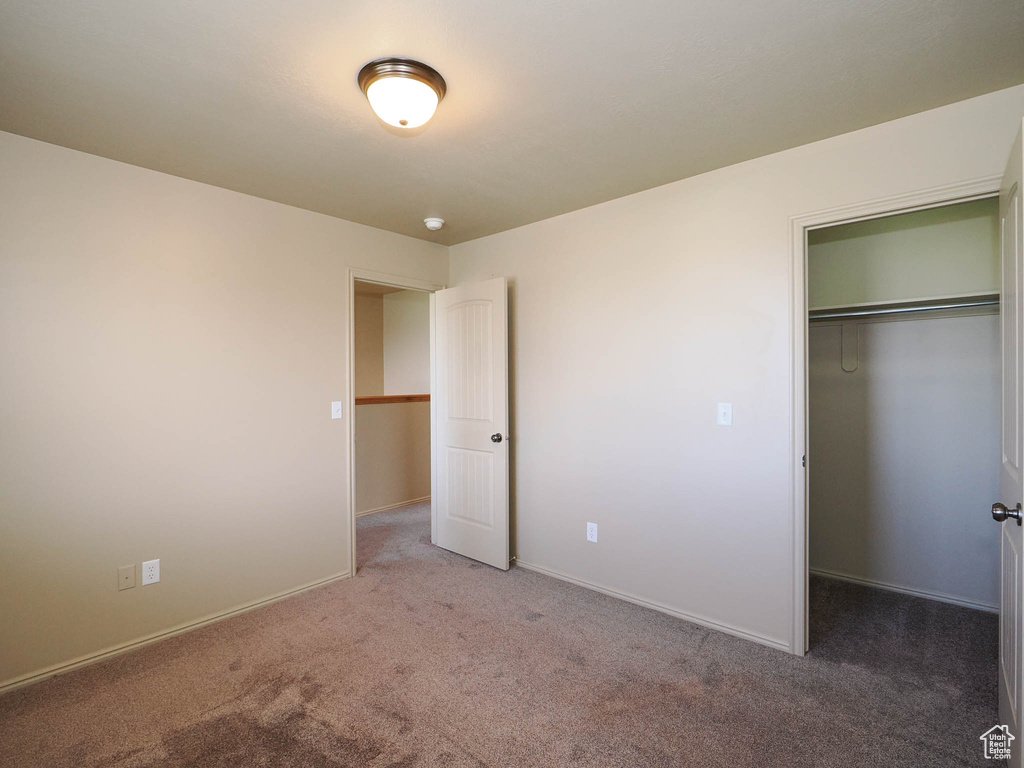 Unfurnished bedroom with a closet and dark colored carpet
