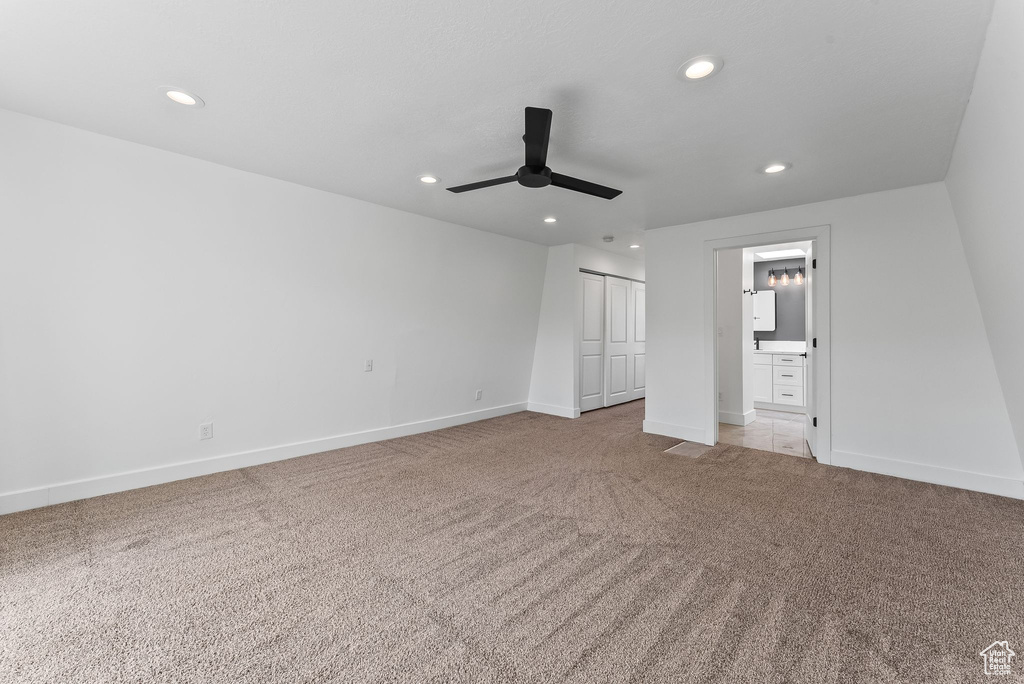 Unfurnished bedroom with a closet, light carpet, ceiling fan, and ensuite bathroom