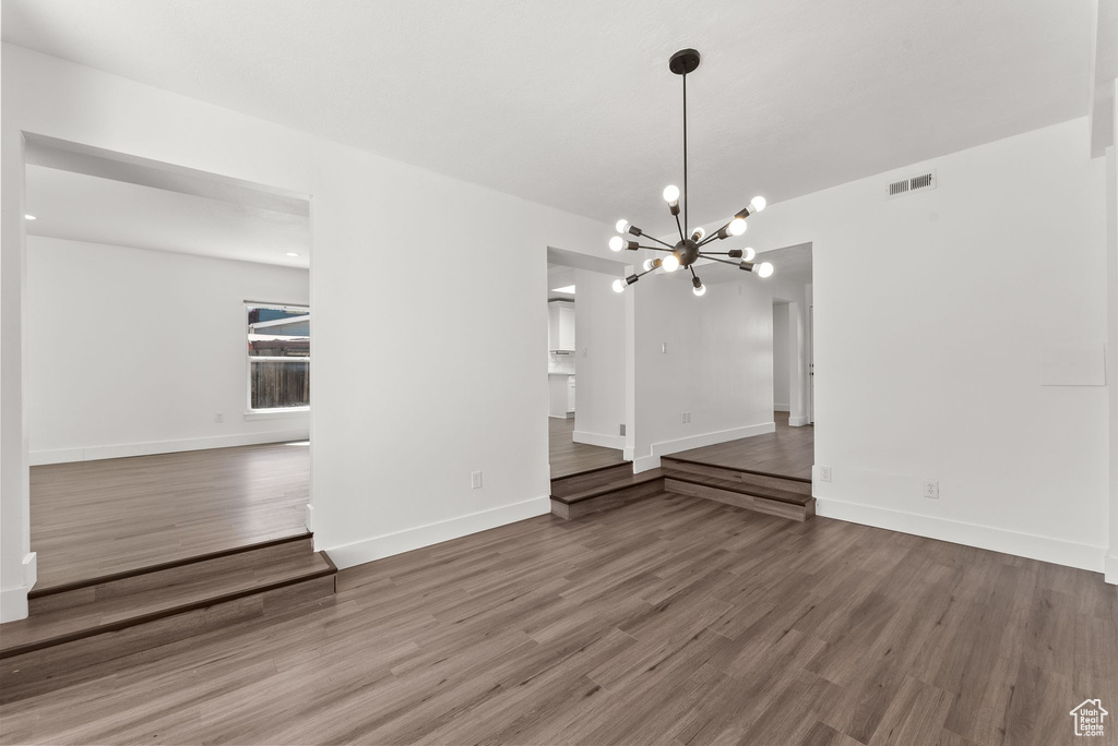 Unfurnished room featuring an inviting chandelier and hardwood / wood-style floors
