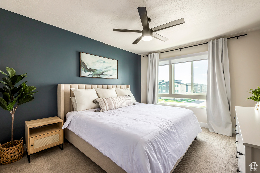 Bedroom with a textured ceiling, carpet floors, and ceiling fan