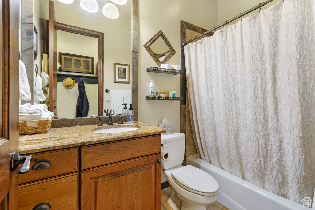 Full bathroom featuring vanity with extensive cabinet space, toilet, and shower / bath combo