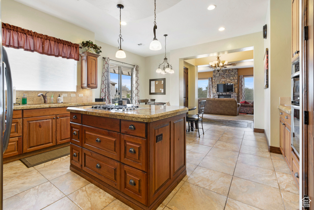 Kitchen featuring backsplash, a kitchen island, an inviting chandelier, and light tile floors