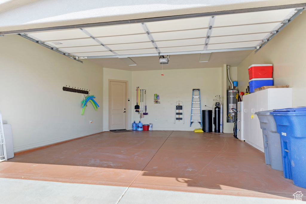 Garage with strapped water heater and a garage door opener